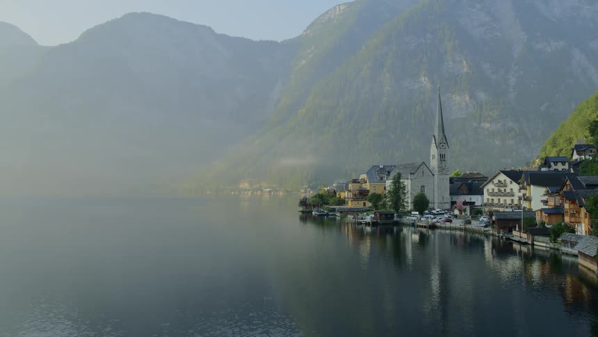Fog obscures mountain range bordering picturesque village and lake