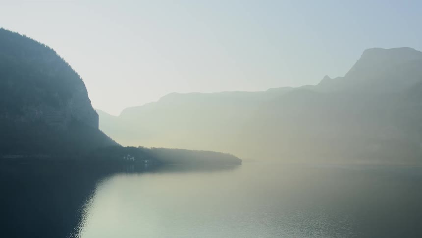 View of mountain ranges next to the lake covered by fog at dawn