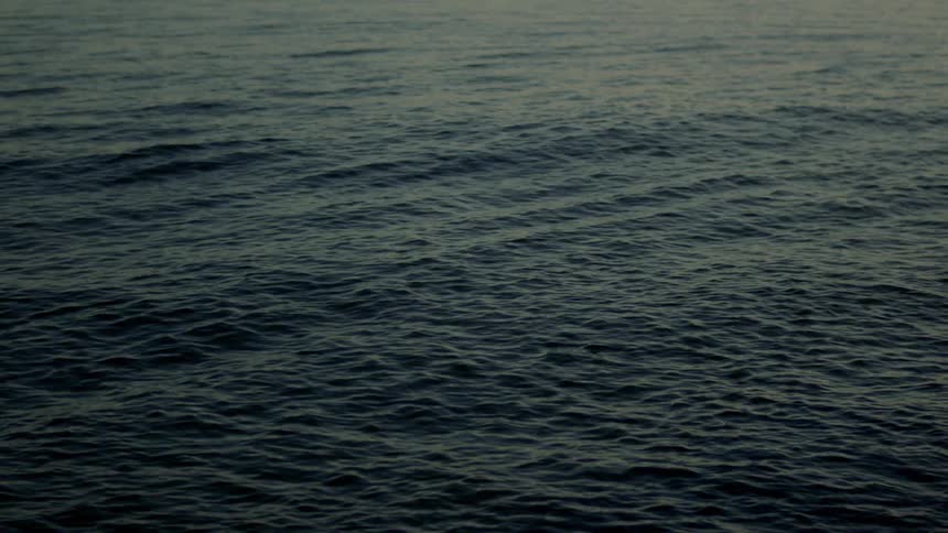 Ripples and subtle waves spread across the surface of the open ocean