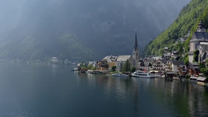 A very lovely looking town with nice architecture sits at the shore of a large body of water and at the base of some mountains