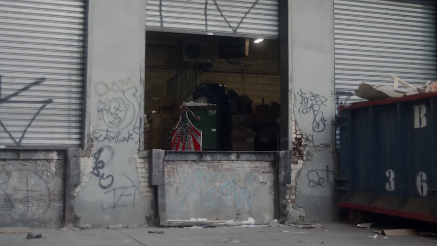 A graffiti covered loading dock with a full dumpster and garbage