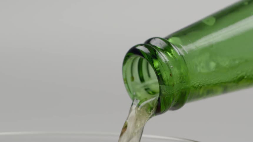 A beverage is poured from a green bottle