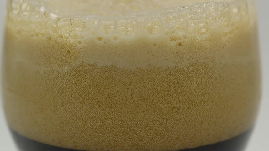 Thick foam forms on top of a glass of dark stout