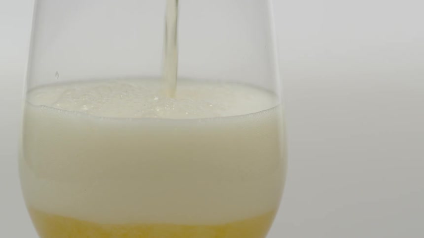 Beer is being poured into a wine glass