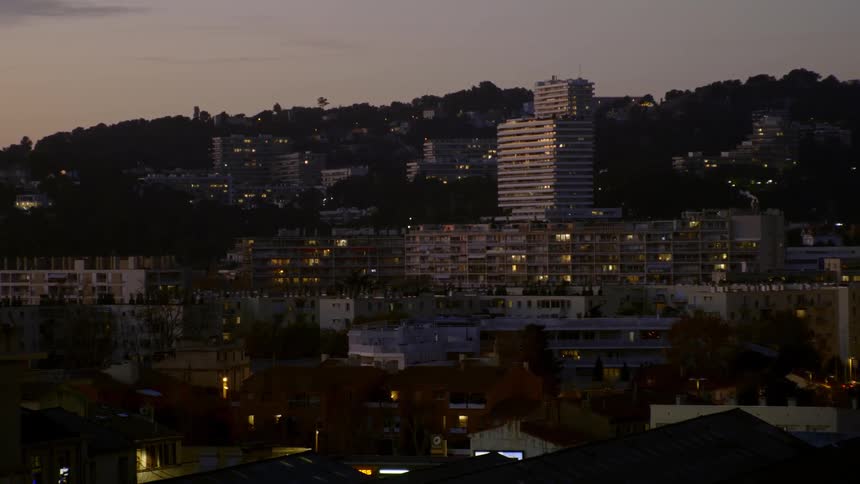 A hillside town with lights shining from the buildings