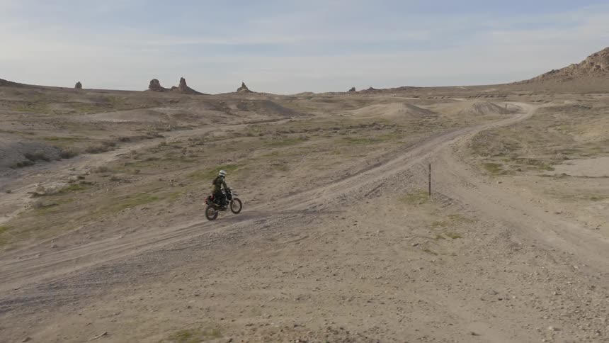 A man rides a motorcycle through a barren desert