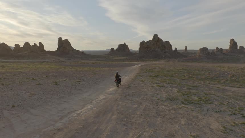 A person riding a motorbike through a desert towards the badlands
