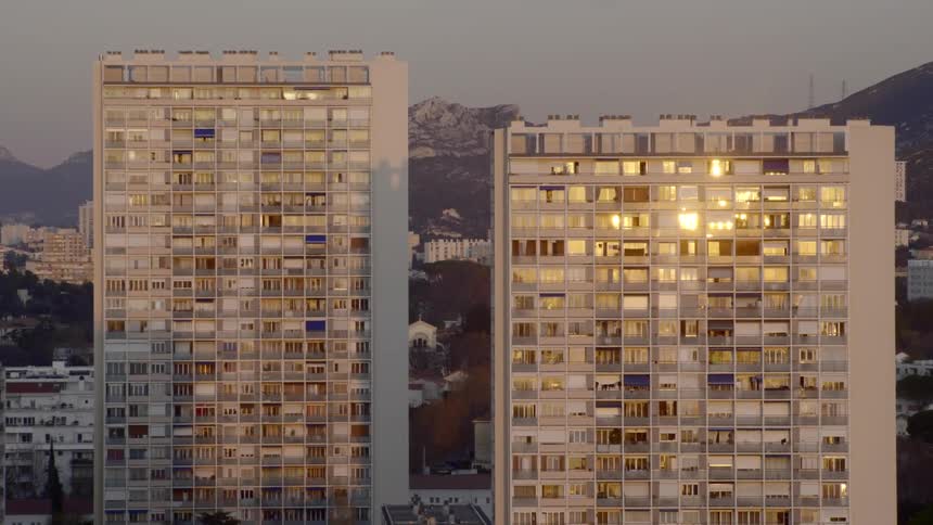 Tall apartment buildings sit in a neighborhood with views of a mountain range