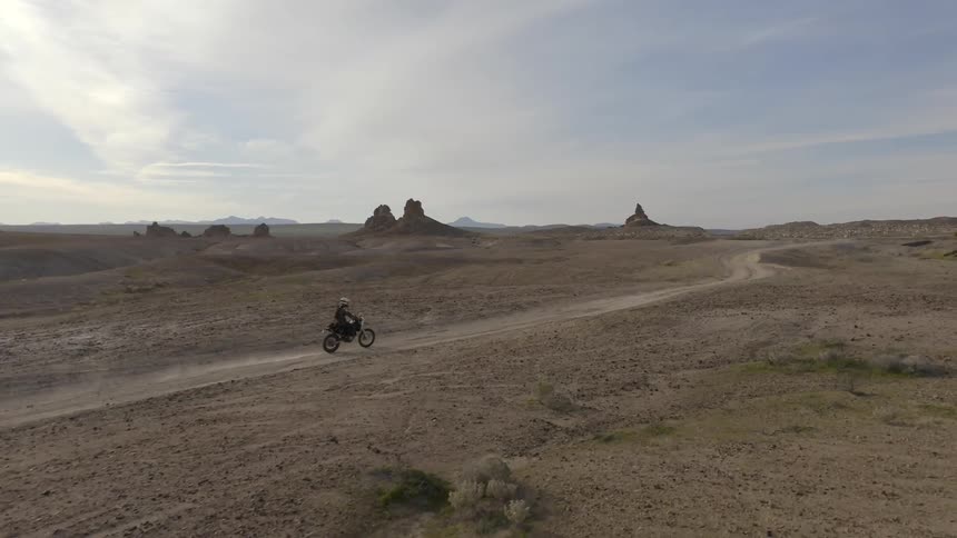 A person riding a dirt bike through badlands