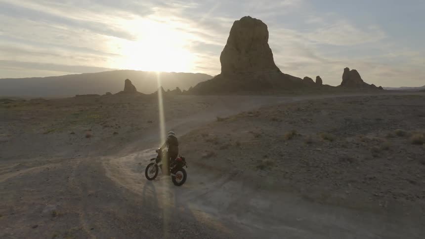 A person rides a dirt bike through a desert path