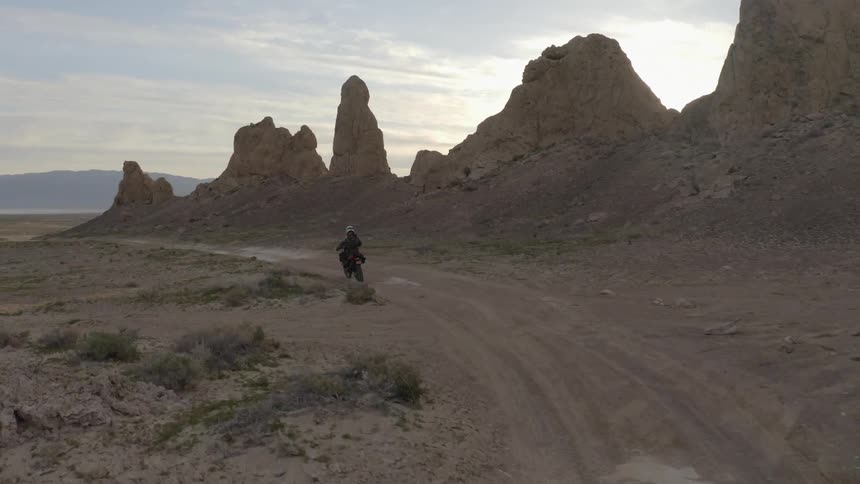 A motorcyclist rides down a dirt trail in the desert