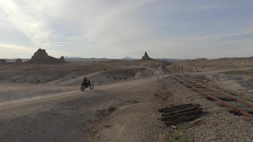 A person rides a dirt bike on a dirt road in the desert