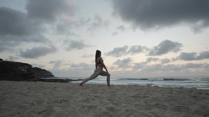 A woman doing stretches on the beach