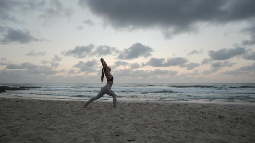 A young woman stretches on a beach
