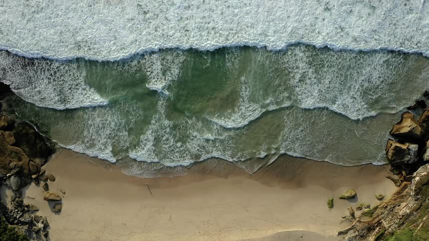 Ocean waves come to shore on the sandy beach of a cove