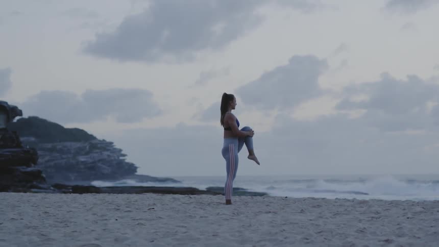 Woman balances and stretches on beach