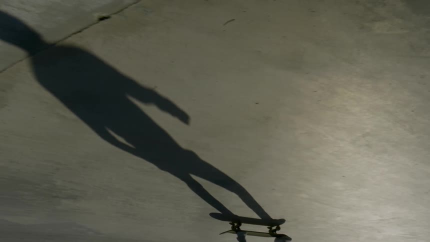 Skateboarders cast long shadows at skate park
