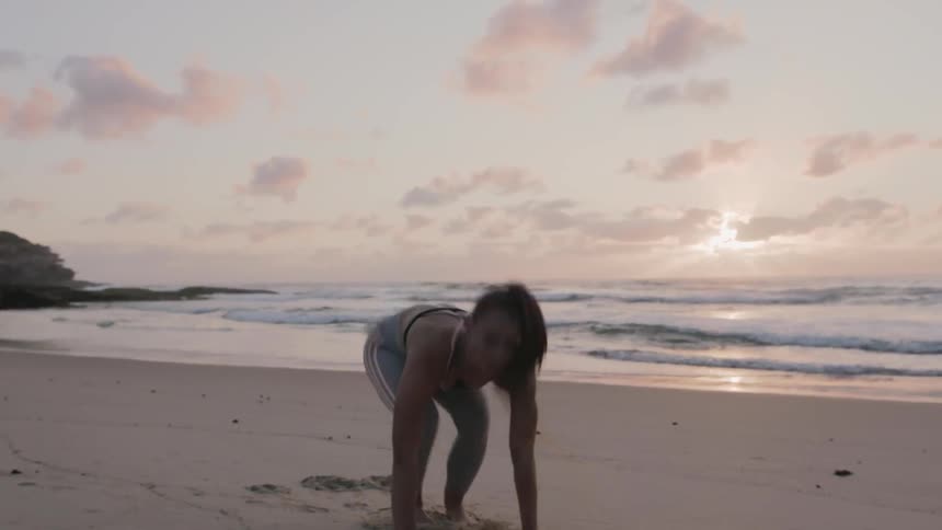 A woman works out on the beach at sun rise