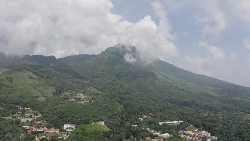 Clouds cover a mountain peak beside a small hillside town