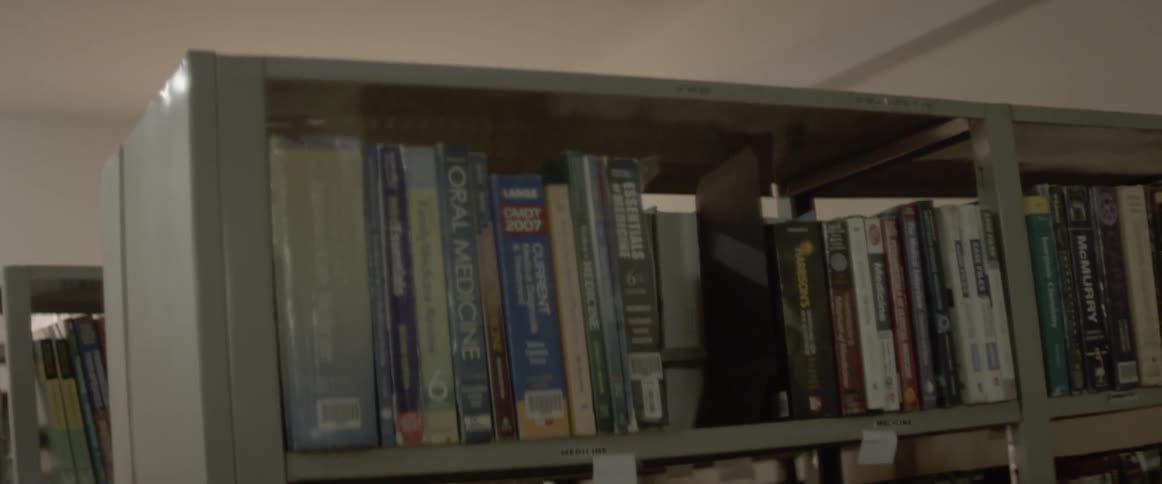 A ceiling fan turns above metal book shelves lined with books