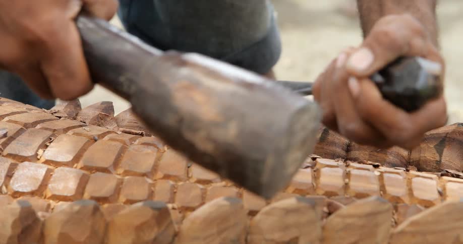A man chisels away at a wood carving