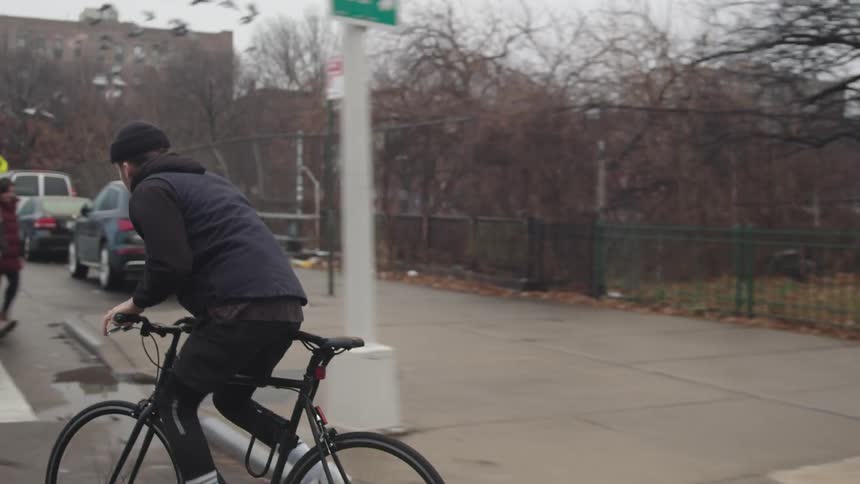 A man riding a bike down a city street on a cloudy day