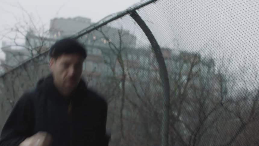A man runs along a pedestrian bridge in a city in drab weather