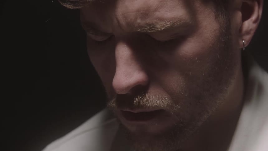 A man contemplating with his eyes closed in a dark room