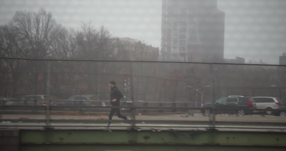 A man runs along a bridge and a bicycle passes him