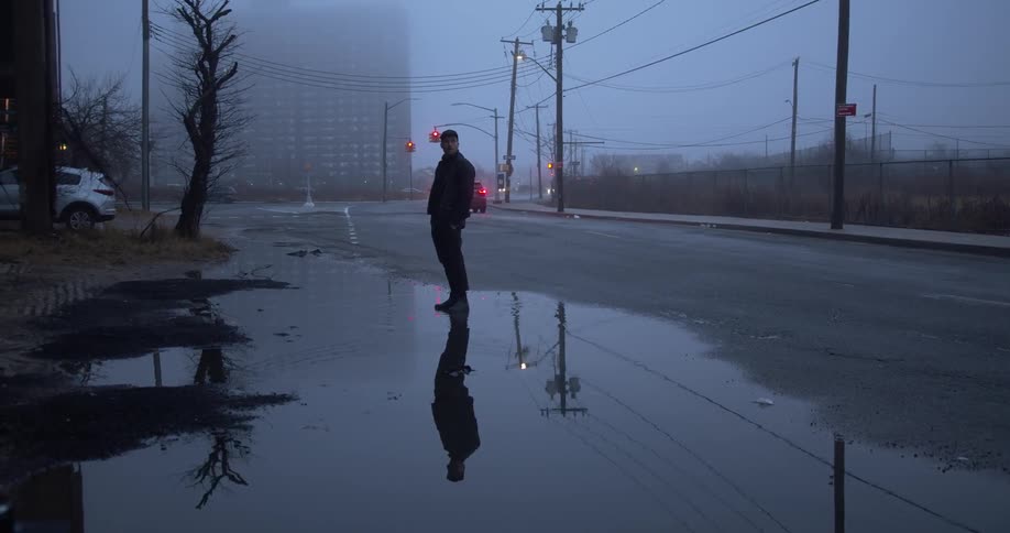 Man stands on street in puddle on foggy day