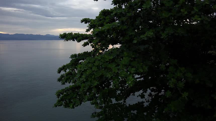 The sun rising over a lake near a wooden gazebo