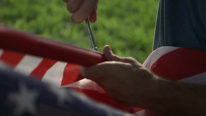 A man uses a tool on a flagpole