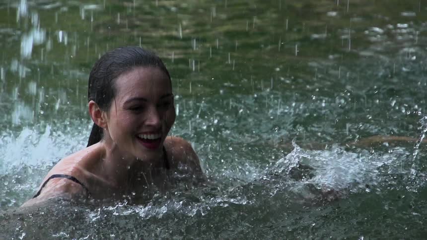 A woman swimming as water falls on her