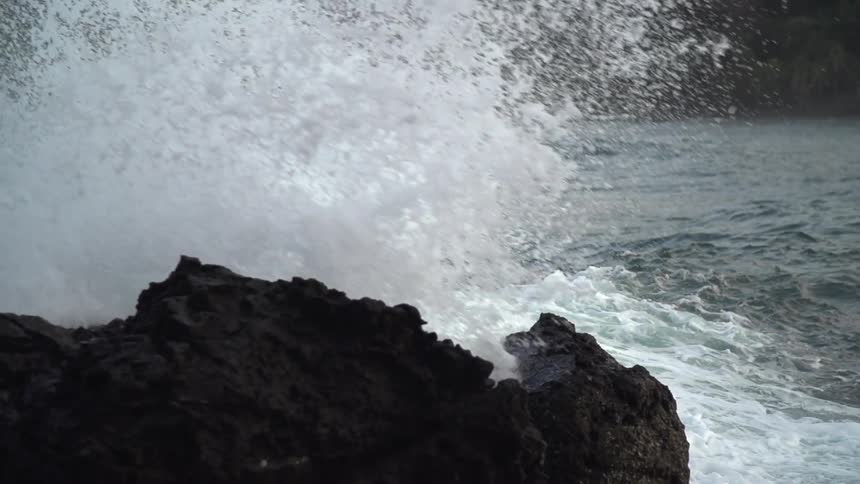 Waves crash against rocks on a cloudy day