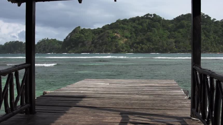 A pier looking out on a tropical cove under a stormy sky