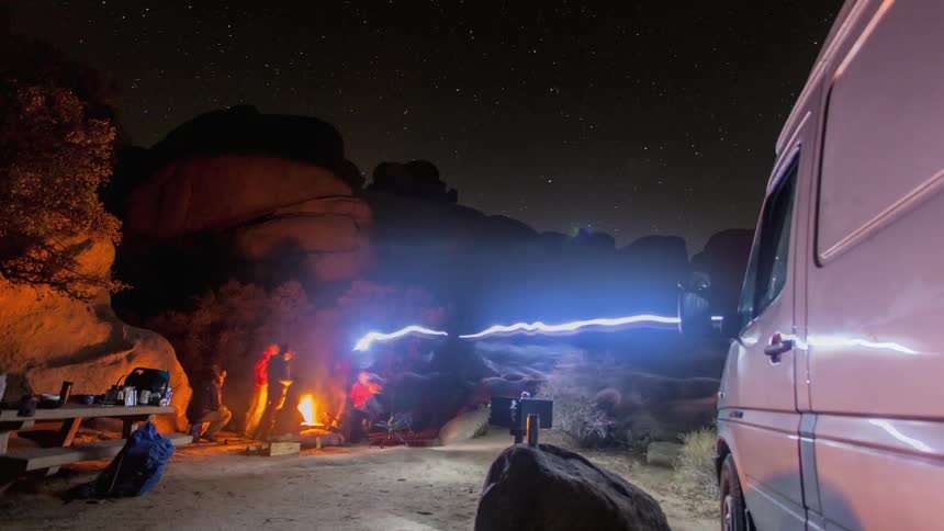 Campers gather around a campfire at night