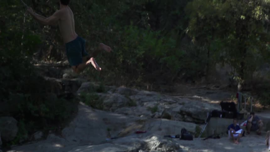 A man swings into a lake in the woods