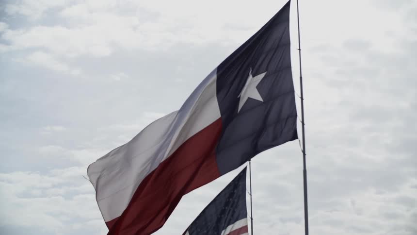 The texas flag blowing under a cloudy sky
