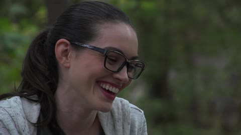 A girl with dark hair and glasses laughing