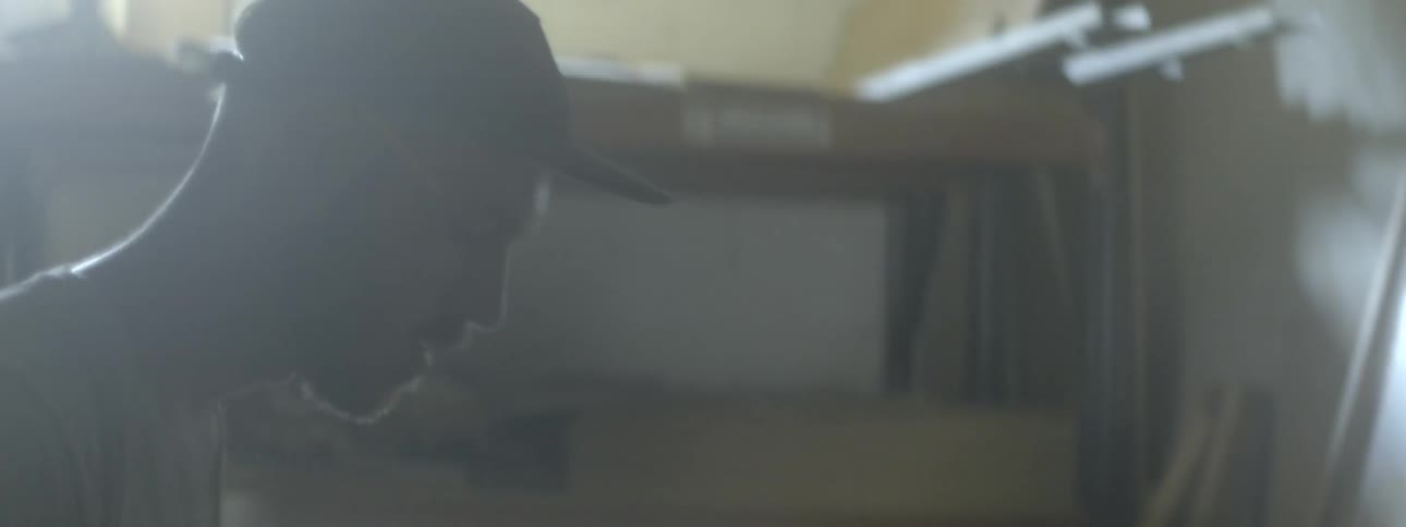 A man in a hat walks around his workshop
