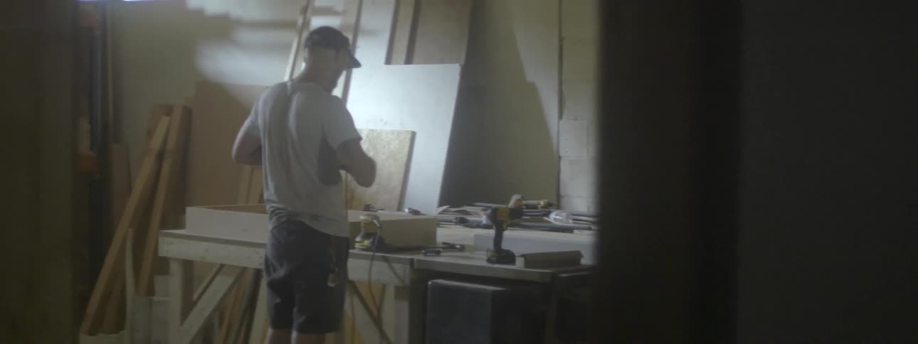 A man plugging a hand sander into an extension cord in a workshop