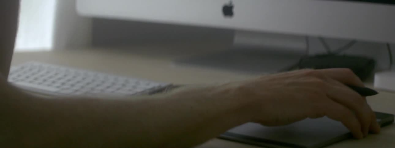 A person adjusts a drawing pad with a stylus in their hand