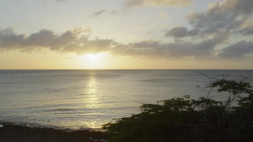 Reveal of the sun rising above an open horizon of calm ocean water