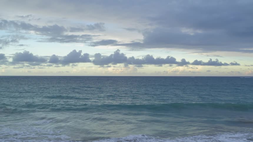 Aerial traverse of ocean waves from an empty beach at dawn