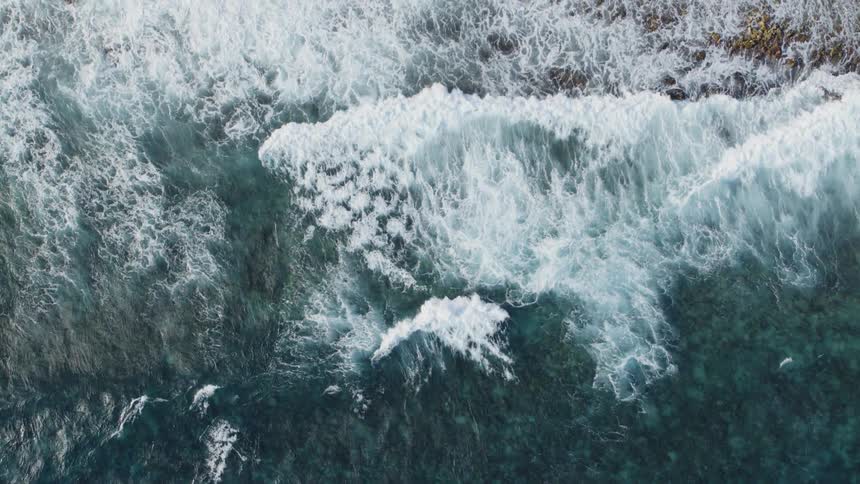 Brilliant navy blue and turquoise ocean waves crash along the beach