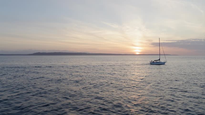 Sailboat motoring in calm waters at sunset