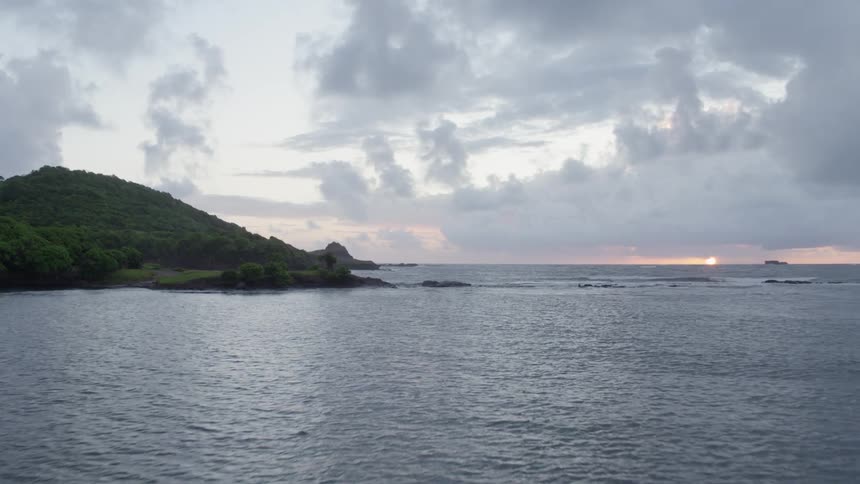 Flying low over tropical island coastline at sunrise