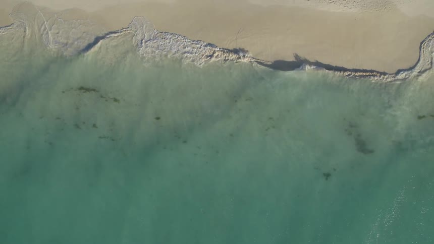 Tropical blue waves break on a white sand beach