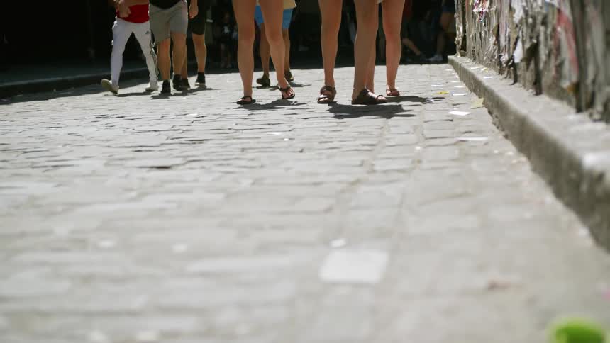 A group of teenagers walks along a brick paved road