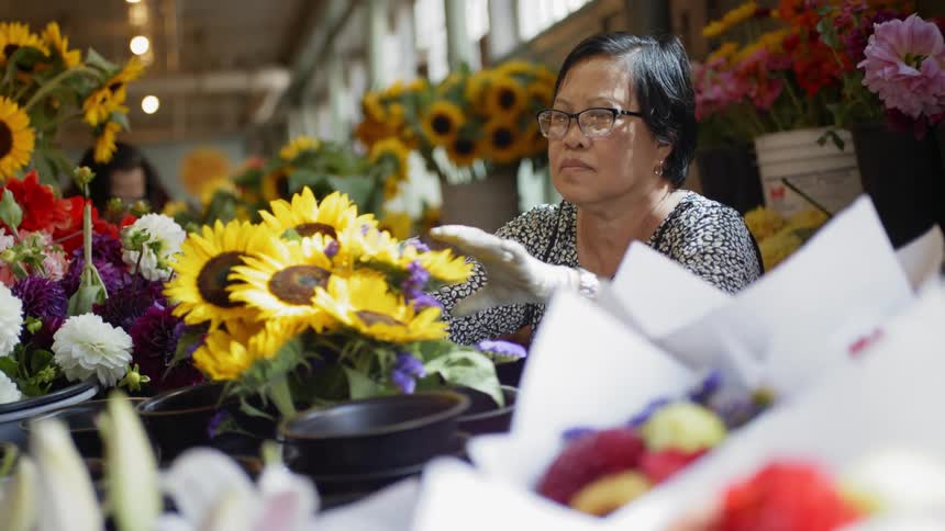 A woman is looking at flowers in a store